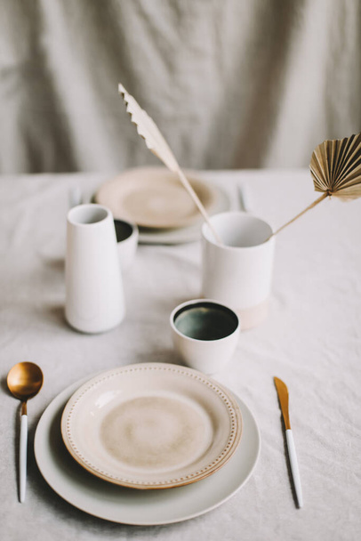 Elegant table setting for fine dining with cutlery, plates, cups on a linen tablecloth. Home decor rustic table setting - 写真・画像