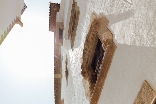Vista en ángulo bajo de fachadas blancas de casas con luz solar y cielo al fondo, Cataluña, España
  - Foto, Imagen
