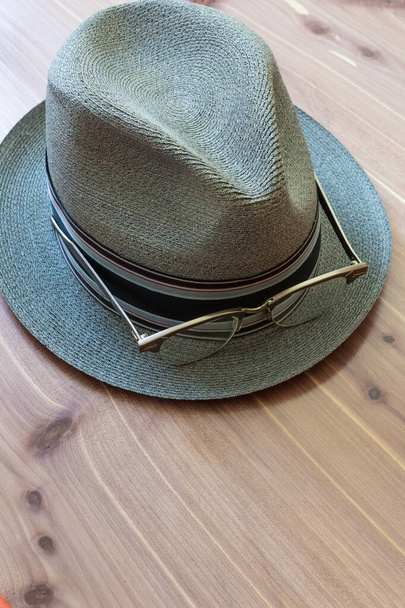 Hipster koncepció fedora kalap és retro kürt keretes szemüveg a peremén, semleges fa háttér, másolás tér, függőleges szempont - Fotó, kép