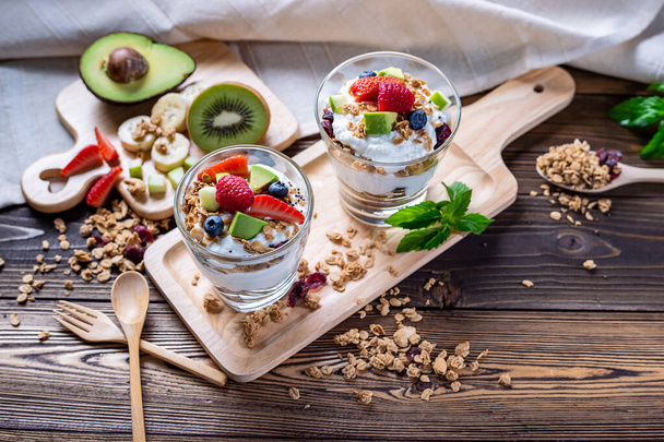 Görög joghurt házi bogyókkal, avokádóval, banánnal és müzlivel. Egészséges étlap és alacsony kalória azoknak, akik diétáznak. kiváló minőségű kép a grafikához és a grafikai tervezéshez - Fotó, kép