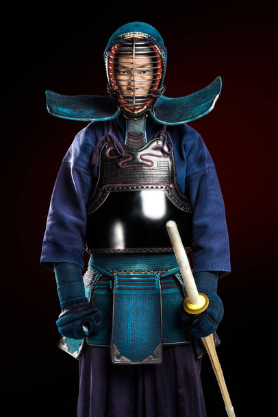 Shinai (bambu kılıcı) ile insan kendo dövüşçüsü portresi. Stüdyoda çekilmiş. Koyu kırmızı arkaplanda kırpma yolu ile izole edilmiş - Fotoğraf, Görsel