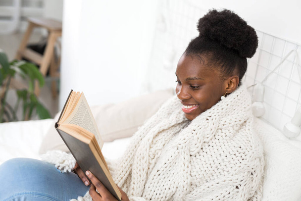 beautiful young african woman sitting on bed with a book - Φωτογραφία, εικόνα