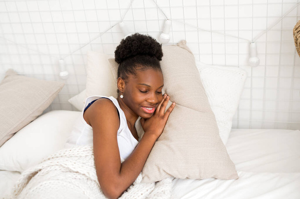  beautiful young african woman sleeping on a white bed - Foto, afbeelding