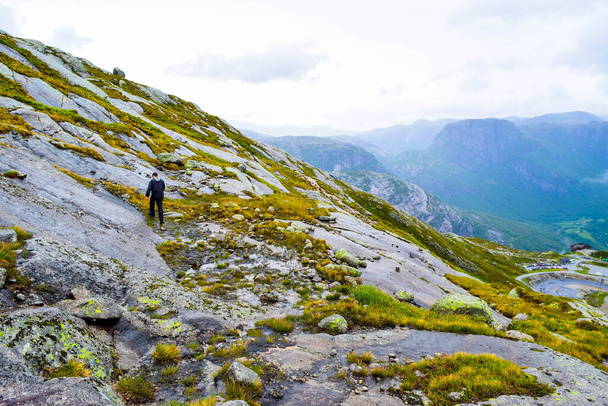 Las cadenas en el camino a la famosa Kjeragbolten ayudan a los turistas a subir acantilados empinados. Kjeragbolten es una roca atascada entre dos montañas sobre el Lysefjorden en el Monte Kierag en el municipio de Forsand, Noruega.
. - Foto, Imagen