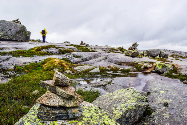 Турист едет в Кьярагболтен. Удивительные пейзажи норвежских гор, где знаменитый валун застрял на высоте 984 метров над Люсефьордом на горе Кьяраг, Норвегия
. - Фото, изображение