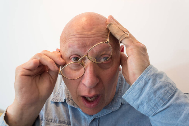 Starší muž s nataženými brýlemi, plešatý, alopecie, chemoterapie, rakovina, izolovaný na bílém, vertikální vzhled - Fotografie, Obrázek
