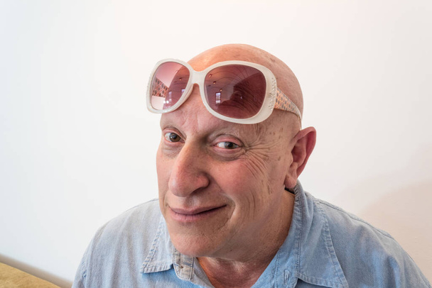 Starší muž s ročníkovými slunečními brýlemi, plešatý, alopecie, chemoterapie, rakovina, izolovaný na bílém, vertikální vzhled - Fotografie, Obrázek