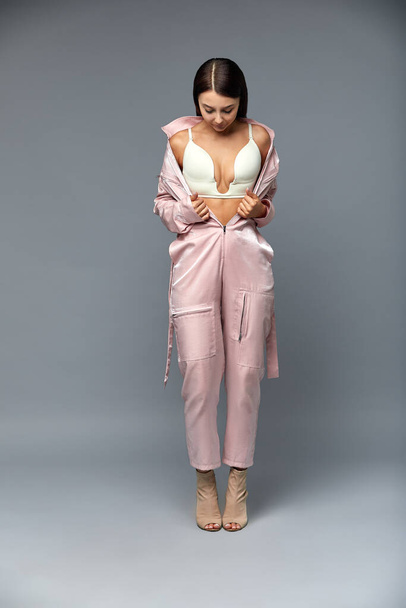 Fashion girl in pink overalls on a gray background. Copy space. - Photo, Image