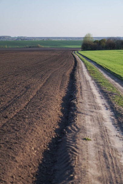 Magnífica estrada de terra fora da cidade em um campo. Caminho preparado desarrumado em um prado na primavera. Fundo de estoque para projeto
 - Foto, Imagem