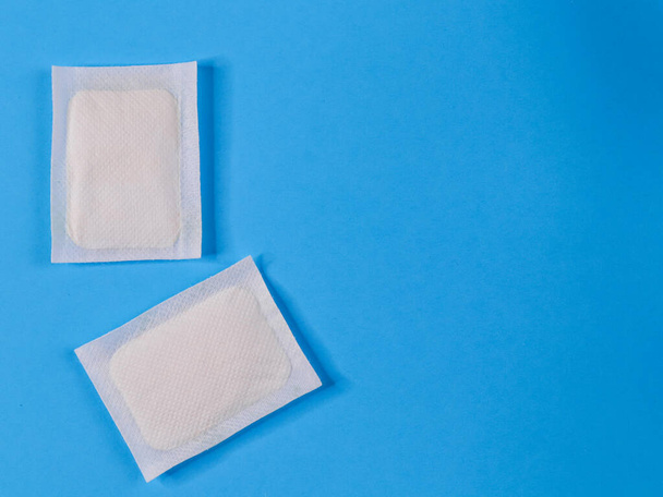 Two adhesive plasters on the left on a blue background. Close up, top view and place for text. - Photo, Image