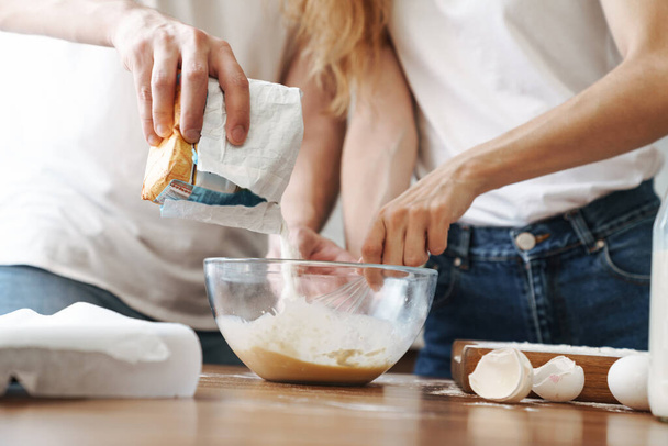 Cropped image of caucasian couple cooking breakfast and mixing dough in kitchen at home - Foto, imagen