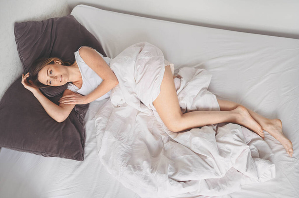 Attraktive lächelnde junge Frau streckt sich im Bett, wacht allein glücklich auf, wacht nach gesundem Schlaf in gemütlichen bequemen Bett und Matratze genießen Sie guten Morgen - Foto, Bild