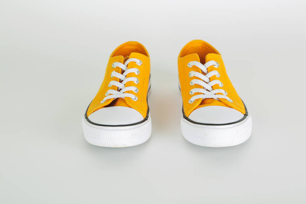 Stylové žluté tenisky boty s bílými tkaničkami na bílém pozadí - Fotografie, Obrázek