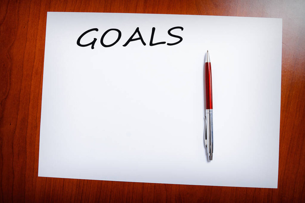 A paper of goals with pen on a wooden background - Photo, Image