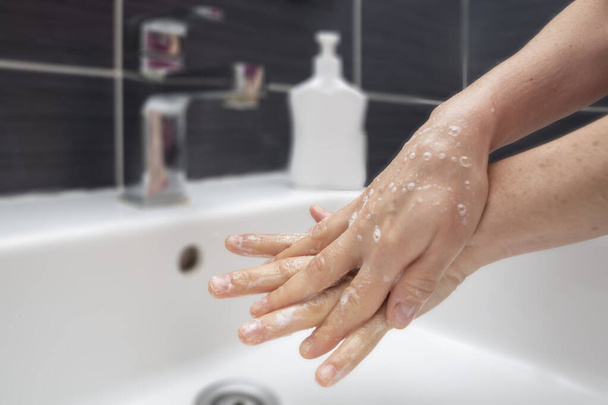 Γυναίκα πλένει τα χέρια με σαπούνι. Ένα αγνώριστο θηλυκό που δείχνει πώς να πλένει σωστά τα χέρια του. Πρόληψη του Coronavirus ή του COVID-19 - Φωτογραφία, εικόνα