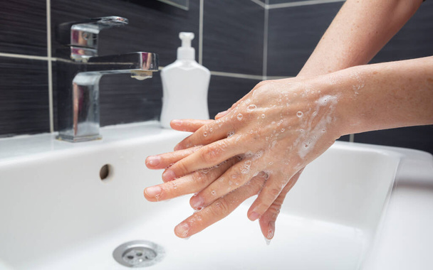 Egy nő kezet mos szappannal. Egy felismerhetetlen nő, aki megmutatja, hogyan kell rendesen kezet mosni. Coronavirus vagy COVID-19 prevenció - Fotó, kép