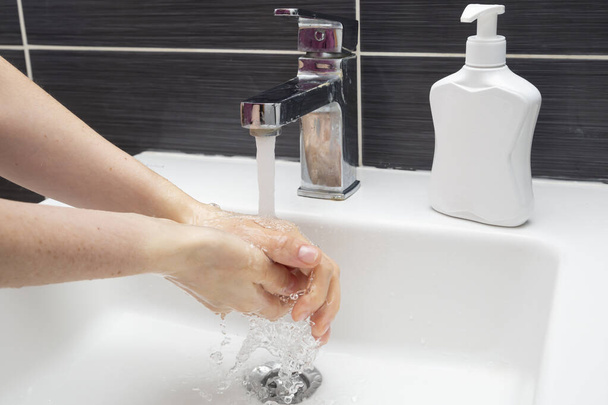 Frau wäscht sich die Hände mit Seife. Ein unkenntlich gemachtes Weibchen zeigt, wie man sich richtig die Hände wäscht. Coronavirus oder COVID-19 Prävention - Foto, Bild