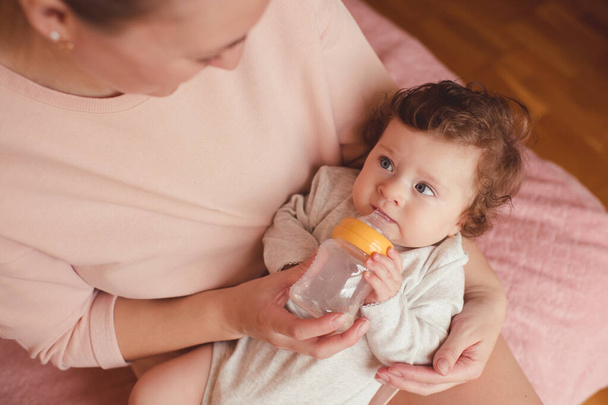 Menina menor de 1 ano bebendo leite de mamadeira segurando por mãe. Nutrição saudável
. - Foto, Imagem