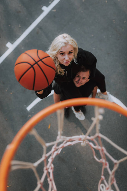 Top widok szczęśliwy młoda dama szkolenia na świeżym powietrzu na boisku do koszykówki ze swoim chłopakiem - Zdjęcie, obraz