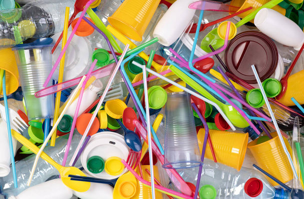 Objetos plásticos desechables de un solo uso como botellas, tazas, tenedores, cucharas y pajitas para beber que causan contaminación del medio ambiente, especialmente los océanos. Vista superior
. - Foto, imagen