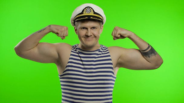 Mladý námořník ukazuje svaly, dívá se do kamery. Námořník v námořnické vestě - Fotografie, Obrázek