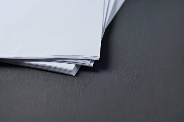 Single scattered heap of blank white paper sheets lies on dark concrete table on workplace of secretary, director, boss or other worker of company. Space for text - Fotoğraf, Görsel