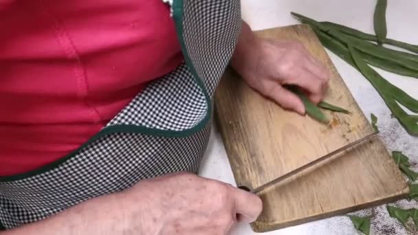 Idősebb hölgy vágás és vágás hüvelyek a konyhában, mielőtt főzni őket - Felvétel, videó