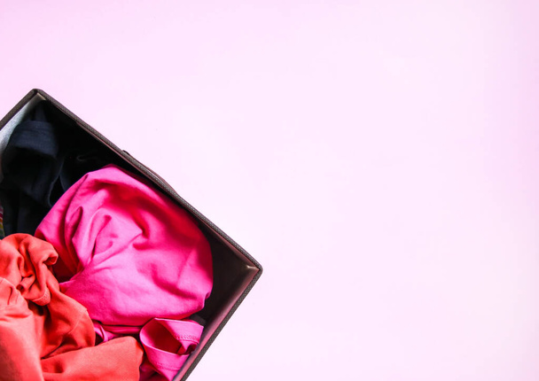 Πολύχρωμα ρούχα κάθετη αποθήκευση στο σπίτι ντουλάπα. Είδη ένδυσης σε υφασμάτινο κουτί σε μαλακό ροζ φόντο - Φωτογραφία, εικόνα