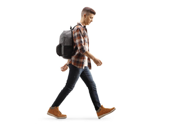 Full length profile shot of a sad male teenage student walking isolated on white background - Фото, зображення