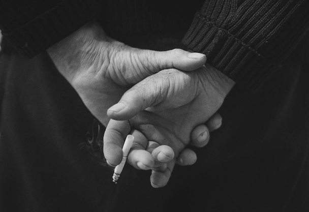 Images en noir et blanc des mains de l'homme tenant une cigarette, concept de tabagisme est nocif pour la santé. Image a du grain ou du bruit
. - Photo, image