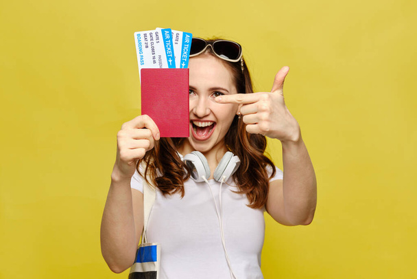 La jeune fille détient un passeport avec des billets et pointe du doigt vers eux. Gros plan
. - Photo, image
