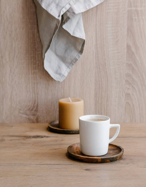 White cup of coffee and caramel candle on wooden background.  - Fotó, kép
