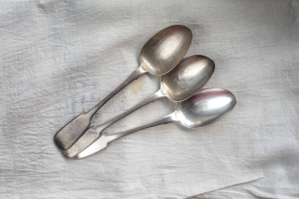 Tres cucharas de plata antiguas sobre un paño blanco
 - Foto, Imagen