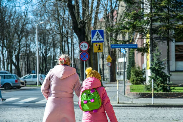 Moeder en dochter gaan van school, familie op een wandeling in het voorjaar - Foto, afbeelding