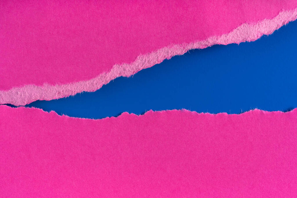青い背景に引き裂かれた紫色の紙の端の破片。柔らかい影で隔離された紙の端を裂いた。紙の破片が縁を引き裂いた。コピースペース,フレーム,バナー - 写真・画像
