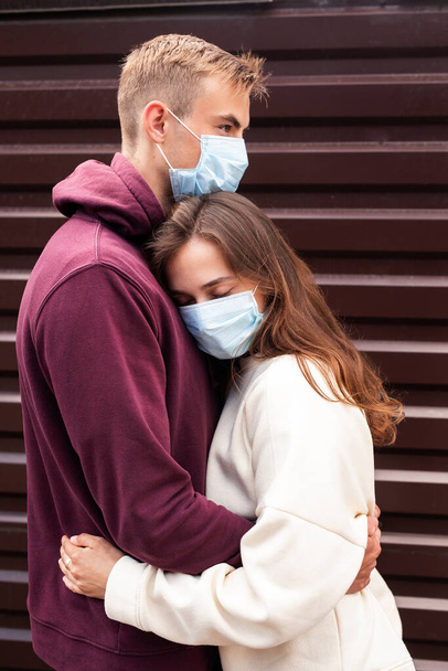 若いカップル抱擁お互いで保護医療マスク屋外で街 - 写真・画像