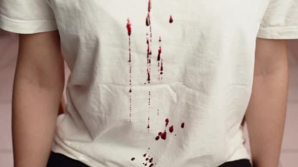 Beyaz tişört boyunca kan damlıyor ve akıyor. Katillerin saldırganlığının ve zorbalığının belirtileri. Mağdur, acı ve acı kavramına karşı suç işleme - Video, Çekim