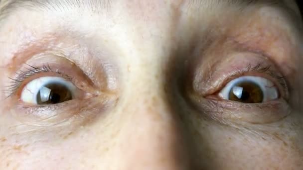 Mature adult woman of Caucasian ethnicity quickly blinks her eyes while looking at camera. Close-up. - Footage, Video