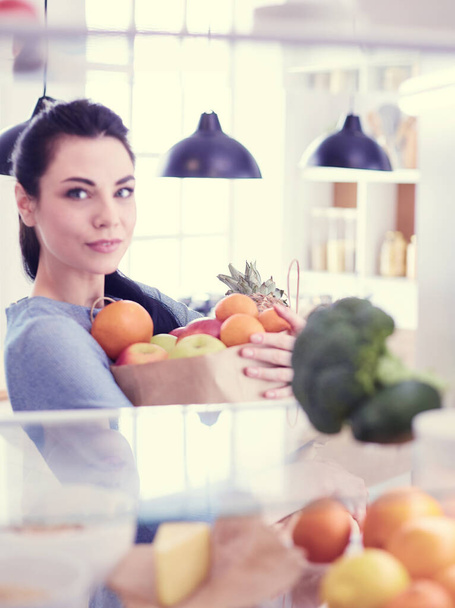 Smiling woman taking a fresh fruit out of the fridge, healthy food concept - Foto, Imagen