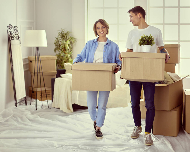 A girl and a guy holding boxes for moving the hands and looking inside box - Foto, imagen