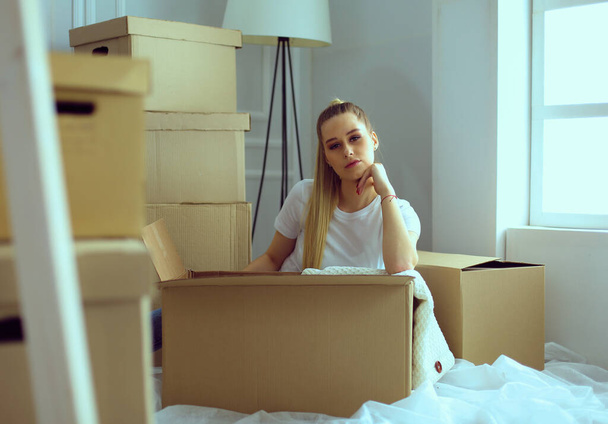 A beautiful single young woman unpacking boxes and moving into a new home - Fotoğraf, Görsel