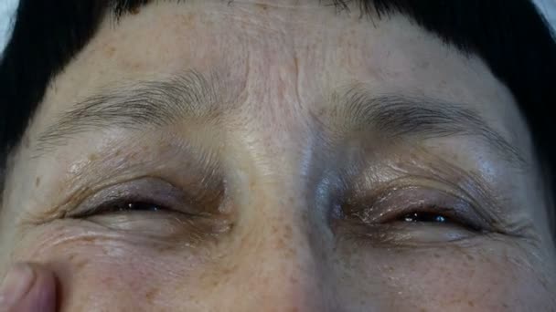 Mature adult woman, caucasian ethnicity touches wrinkles on her face with fingers, looking at camera. Close-up. - Footage, Video