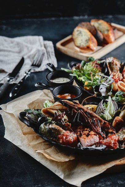 Fresh seafood on a stone table. Oysters, prawns and scallops, squids, served by the chef, beautifully laid out on plates, dark concrete background. - Fotó, kép
