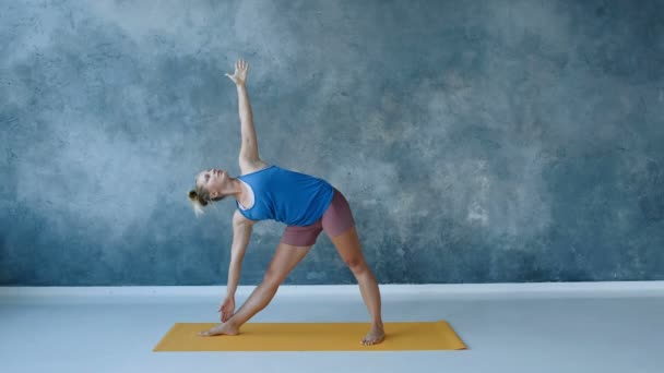 instructor de yoga haciendo postura triangular, estirando los músculos laterales del cuerpo, inclinación del brazo hacia arriba, cámara lenta
 - Metraje, vídeo