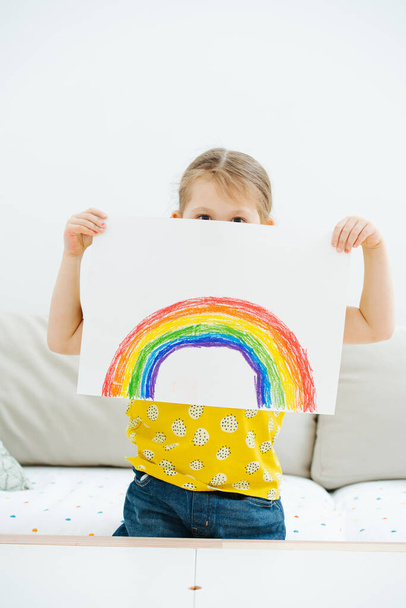 Little girl showing a rainbow she just painted. It partially covering her face. - Valokuva, kuva
