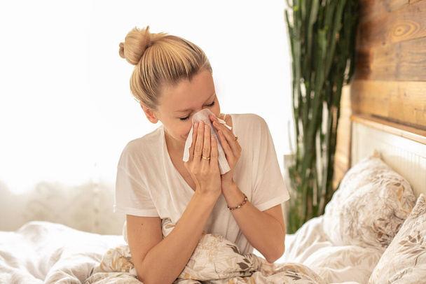 Sick woman lying in bed, wiping her nose . - Фото, зображення
