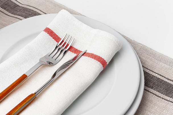 Fork, knife and plate on towel. Isolated on white background. - Foto, Bild