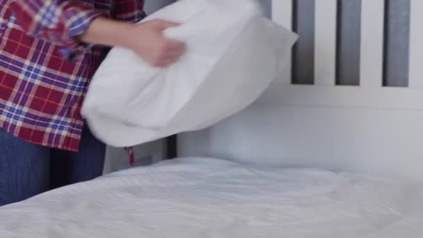 Mujer limpiando su cama en el dormitorio, hermosa hembra establecer y hacer la cama, la organización de sus almohadas y cojines cuidadosamente
 - Metraje, vídeo