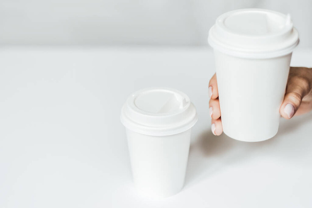 Attrappe einer weiblichen Hand, die eine Kaffeepapiertasse hält. - Foto, Bild