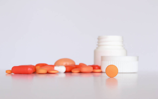 Orange Tablette mit anderen Medikamenten und Plastikflasche auf der Rückseite im selektiven Fokus - Foto, Bild
